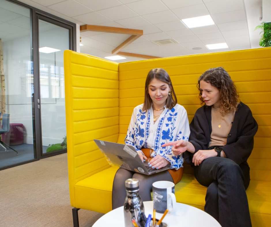 two-girls-on-a-yellow-couch-looking-at-a-computer